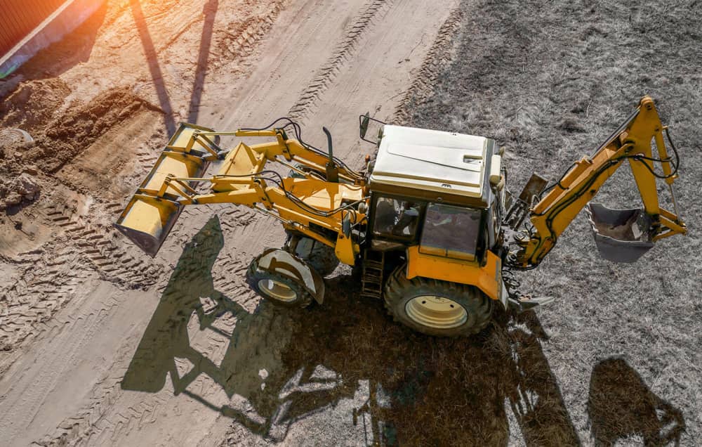 Aerial photo of backhoe driving on construction site 